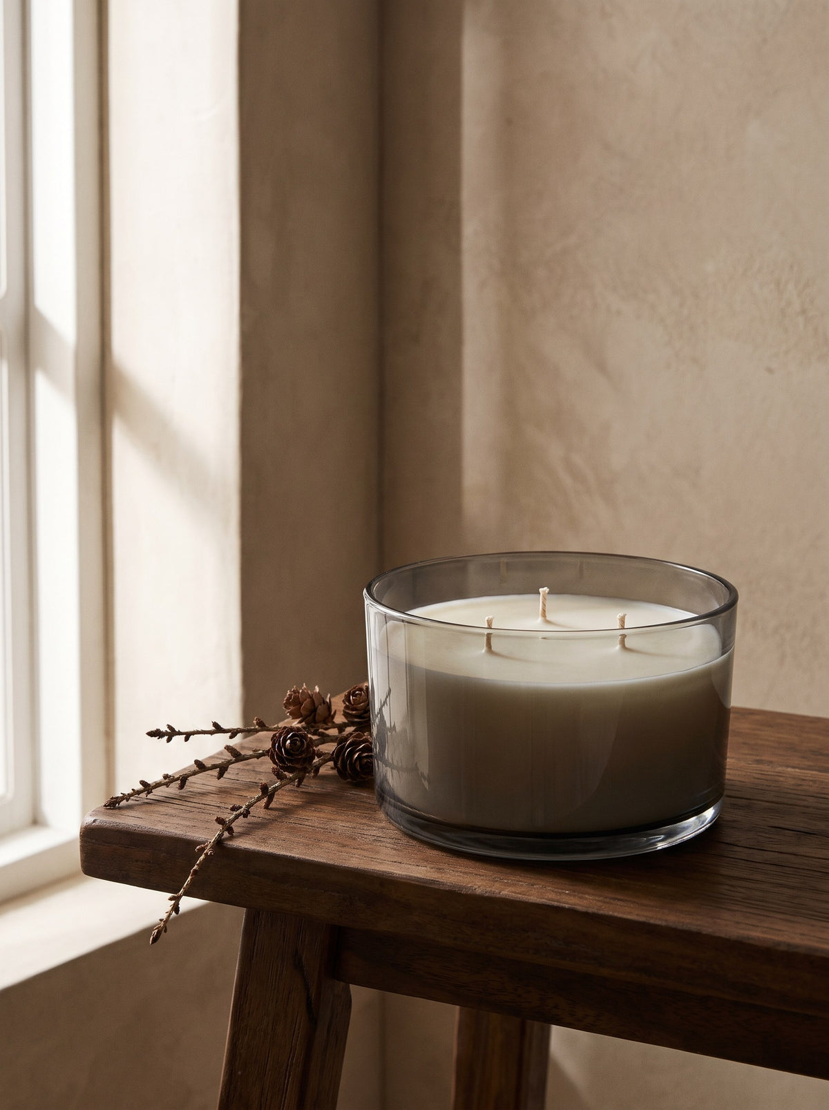 Cedar & Vetiver three-wick candle in a smoked grey glass bowl on a walnut side table