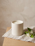 Linen & Neroli candle in a speckled cream stoneware pot on a linen cloth