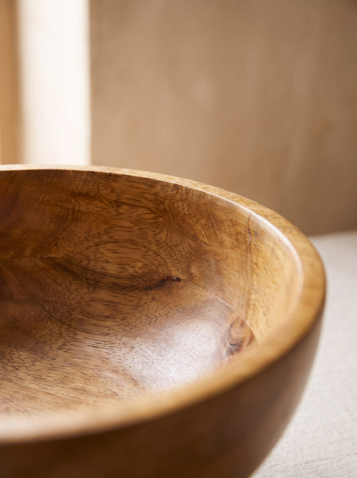 Close-up of the natural wood grain on the rim of the mango wood pedestal bowl