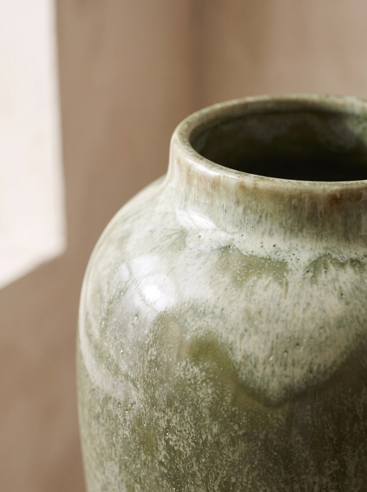 Close-up of the moss green reactive glaze breaking to lighter tones on the vase rim
