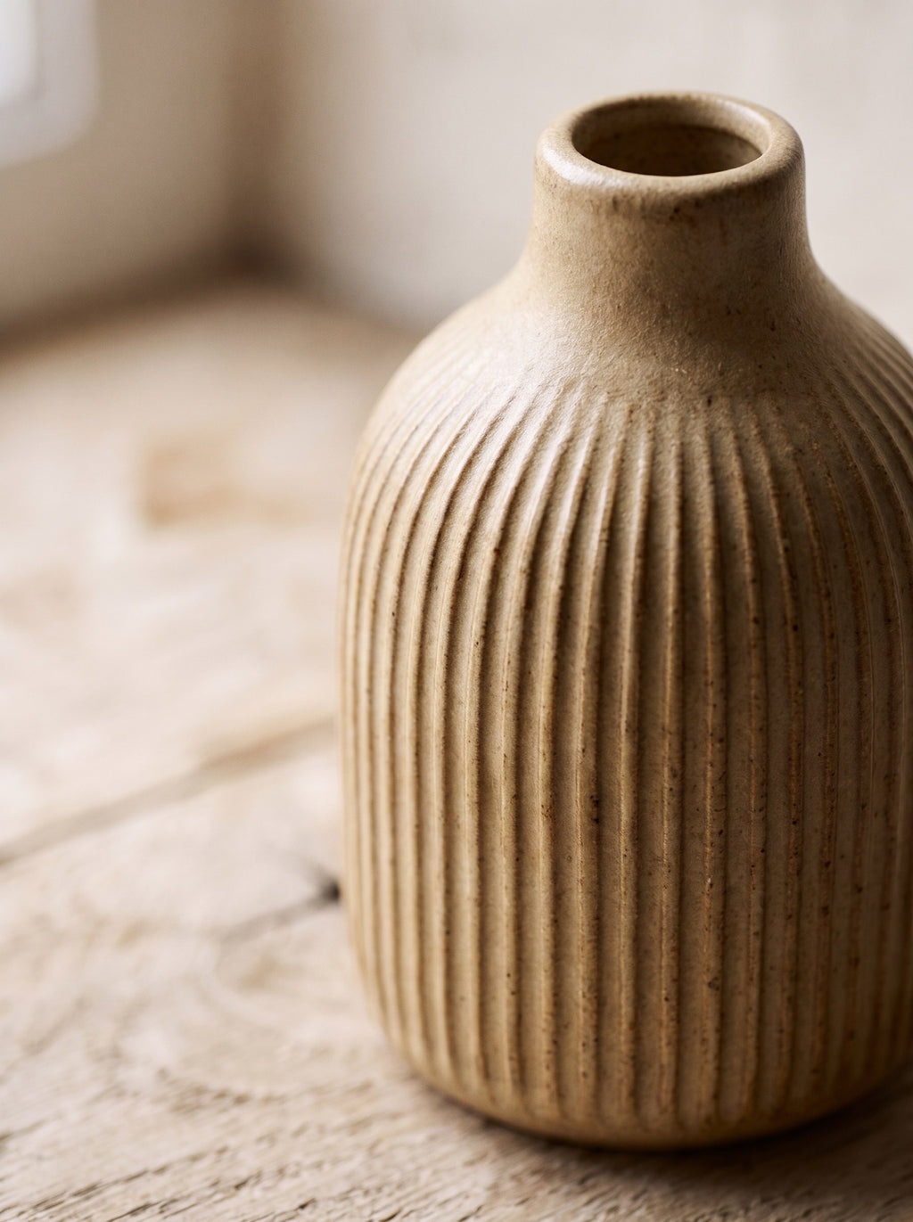 Close-up of the fine vertical ribs and matte sand glaze of the stoneware bud vase