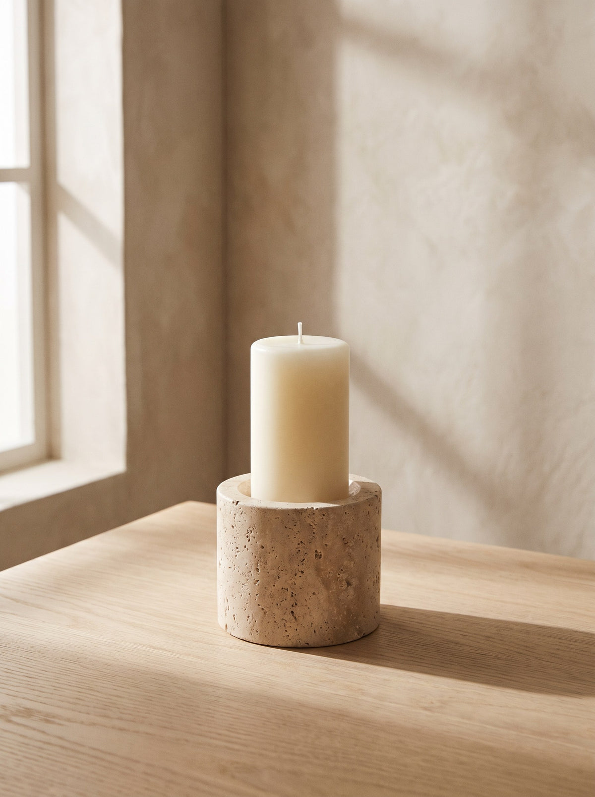 Solid travertine pillar candle holder with an ivory pillar candle, shown for styling