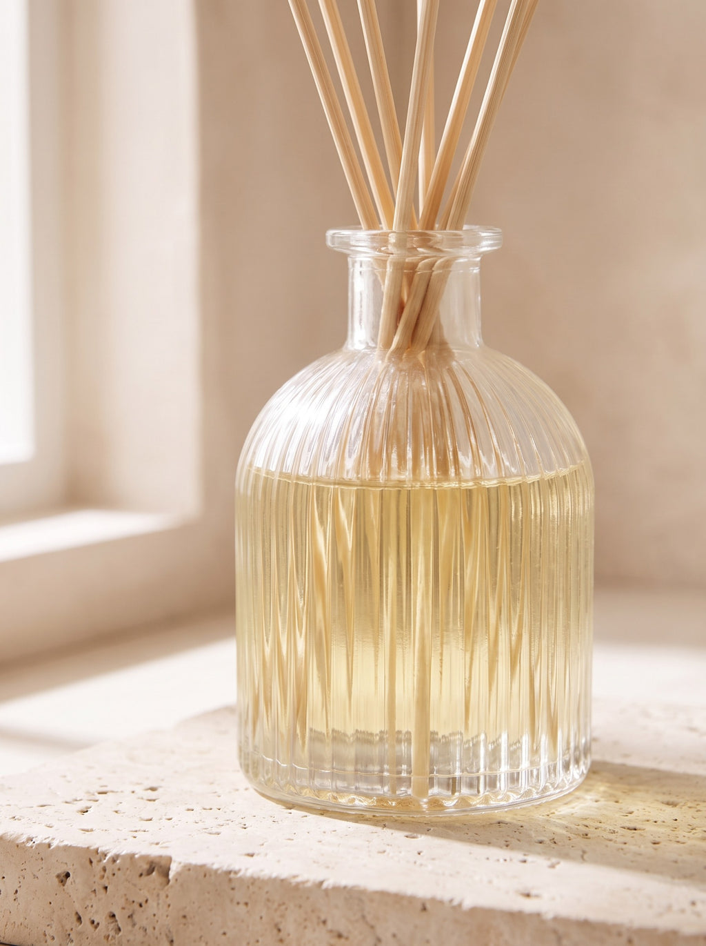 Close-up of the ribbed glass bottle and rattan reeds of the White Tea & Bergamot diffuser