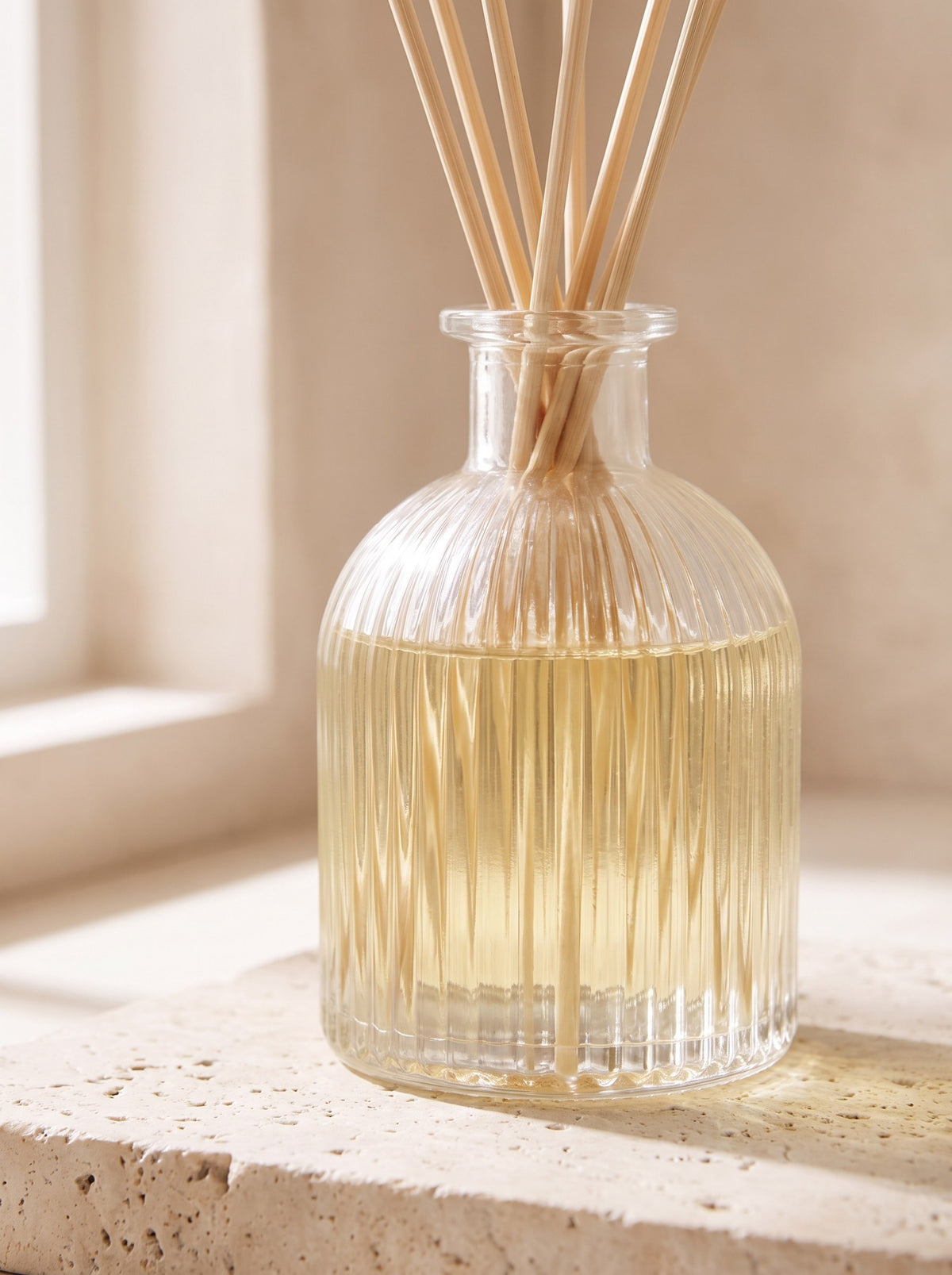 Close-up of the ribbed glass bottle and rattan reeds of the White Tea & Bergamot diffuser
